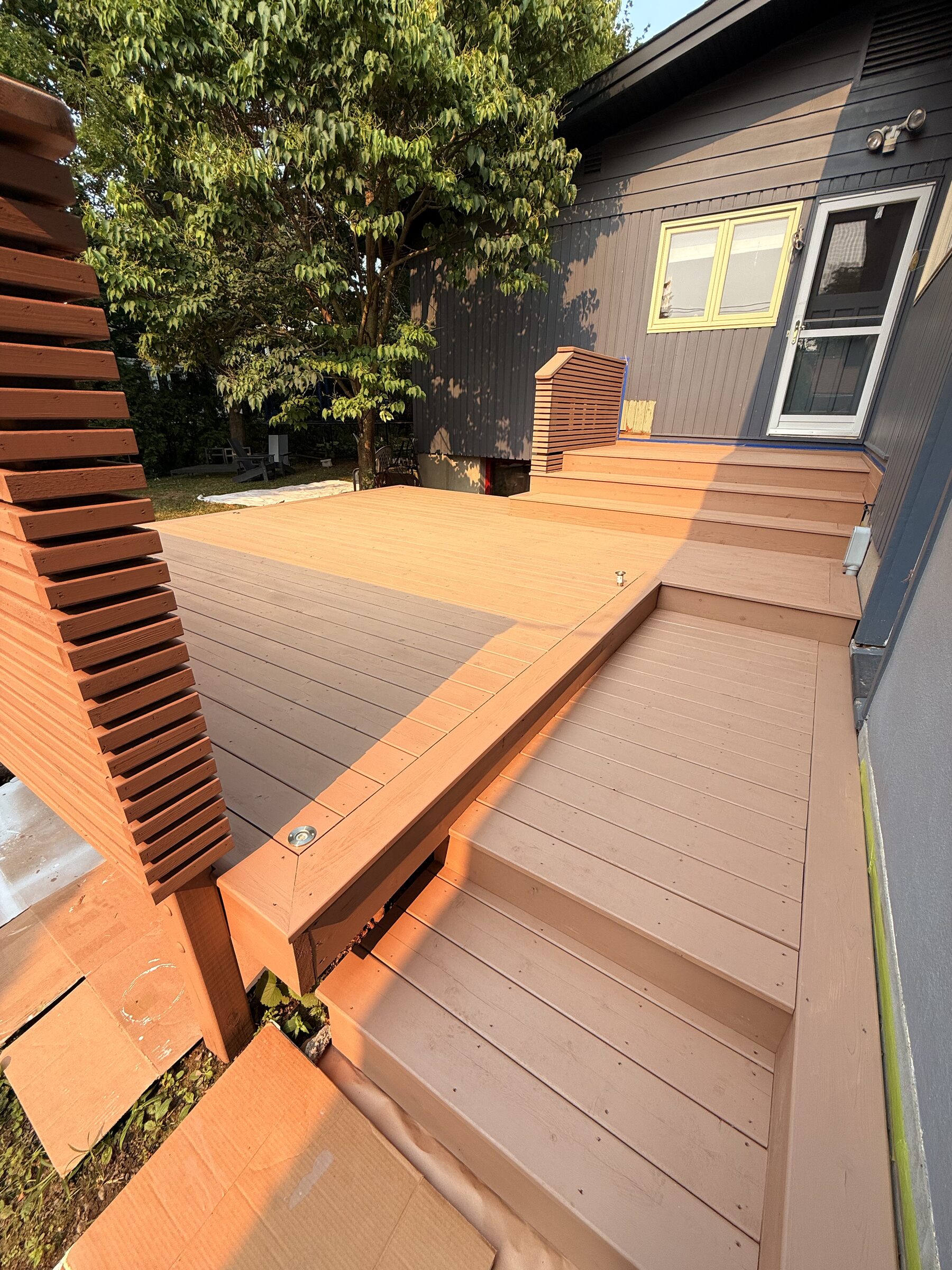 After: Finished deck in a warm reddish-brown stain with a matching slatted privacy wall