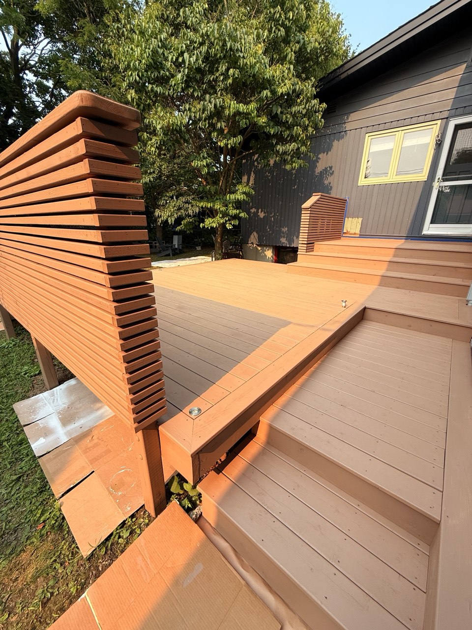 Completed deck renovation with warm freshly stained boards and matching railing, finished on a sunny day.