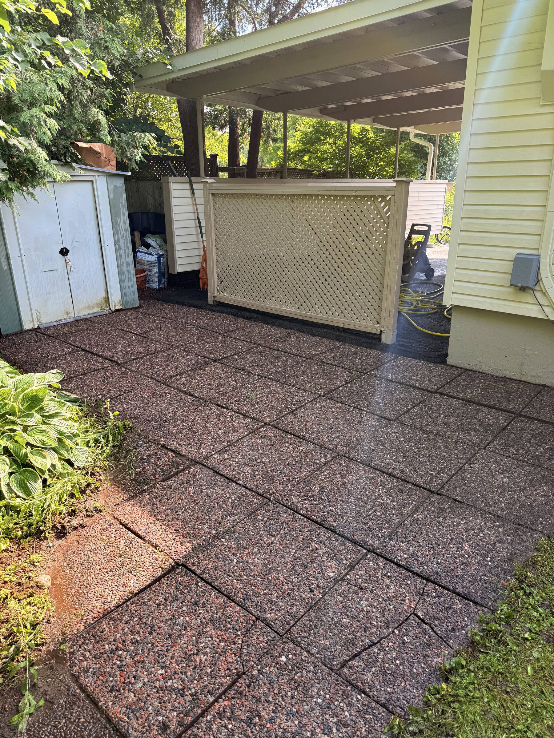 After: Repainted cream carport siding and privacy lattice screen over an exposed-aggregate patio