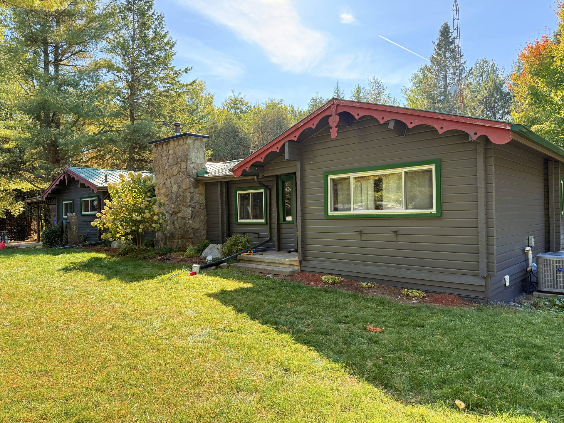 After: Repainted log-cabin-style cottage exterior with restored red gingerbread trim and green window frames