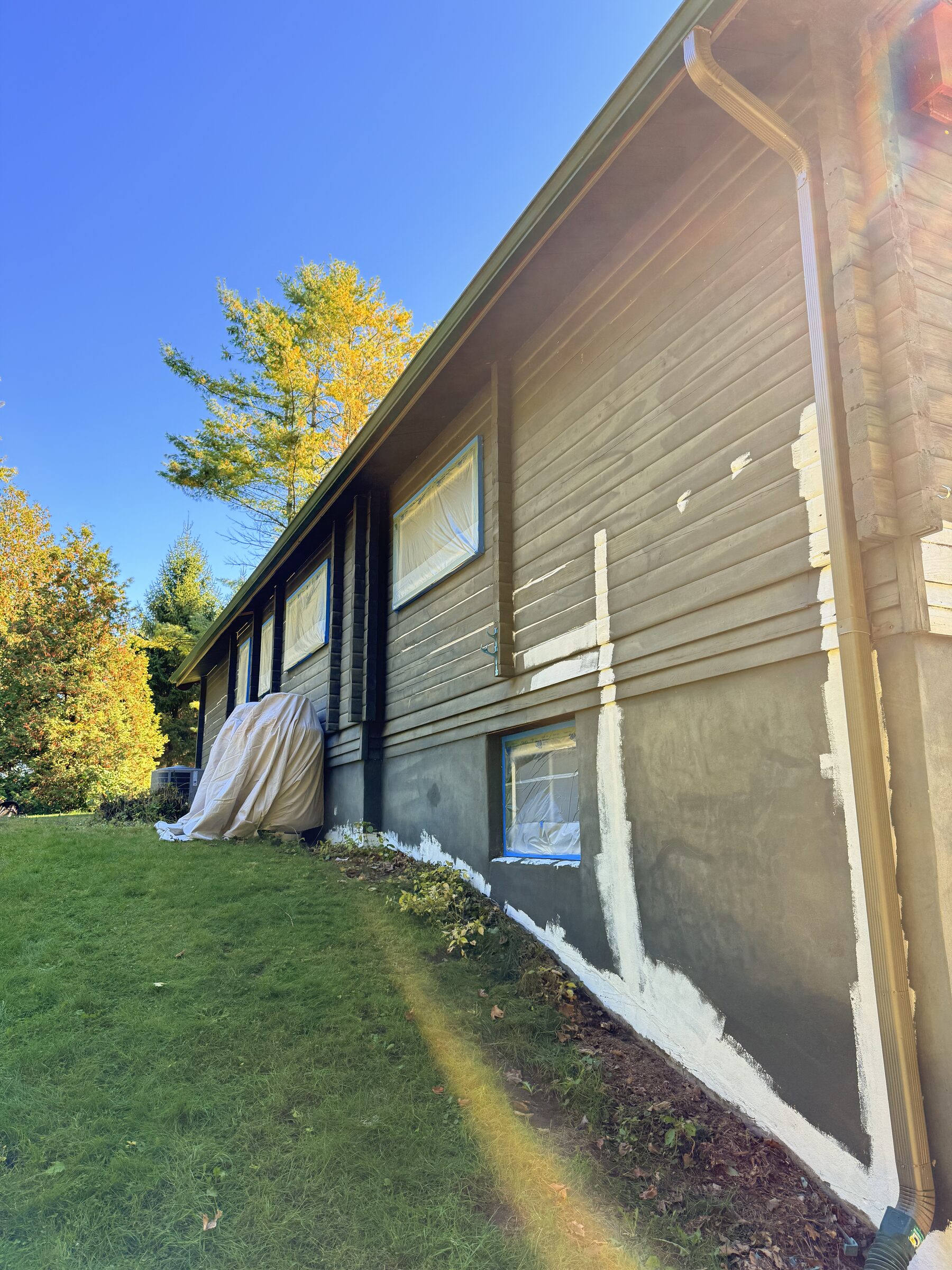 Before: Long single-storey wing with white primer on the lower wall, mid-repaint