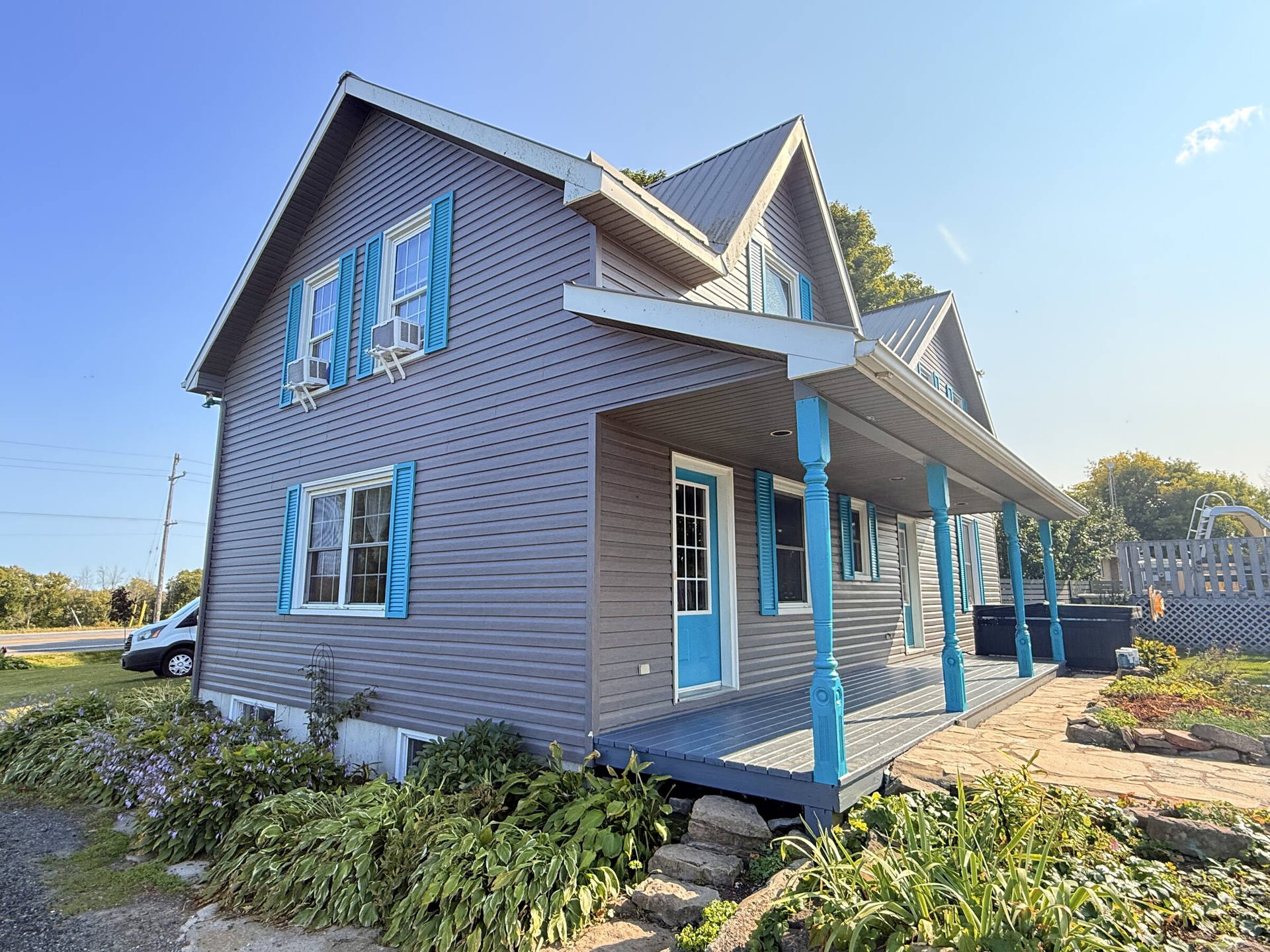 After: Painted wraparound porch with teal turned posts and a matching front door