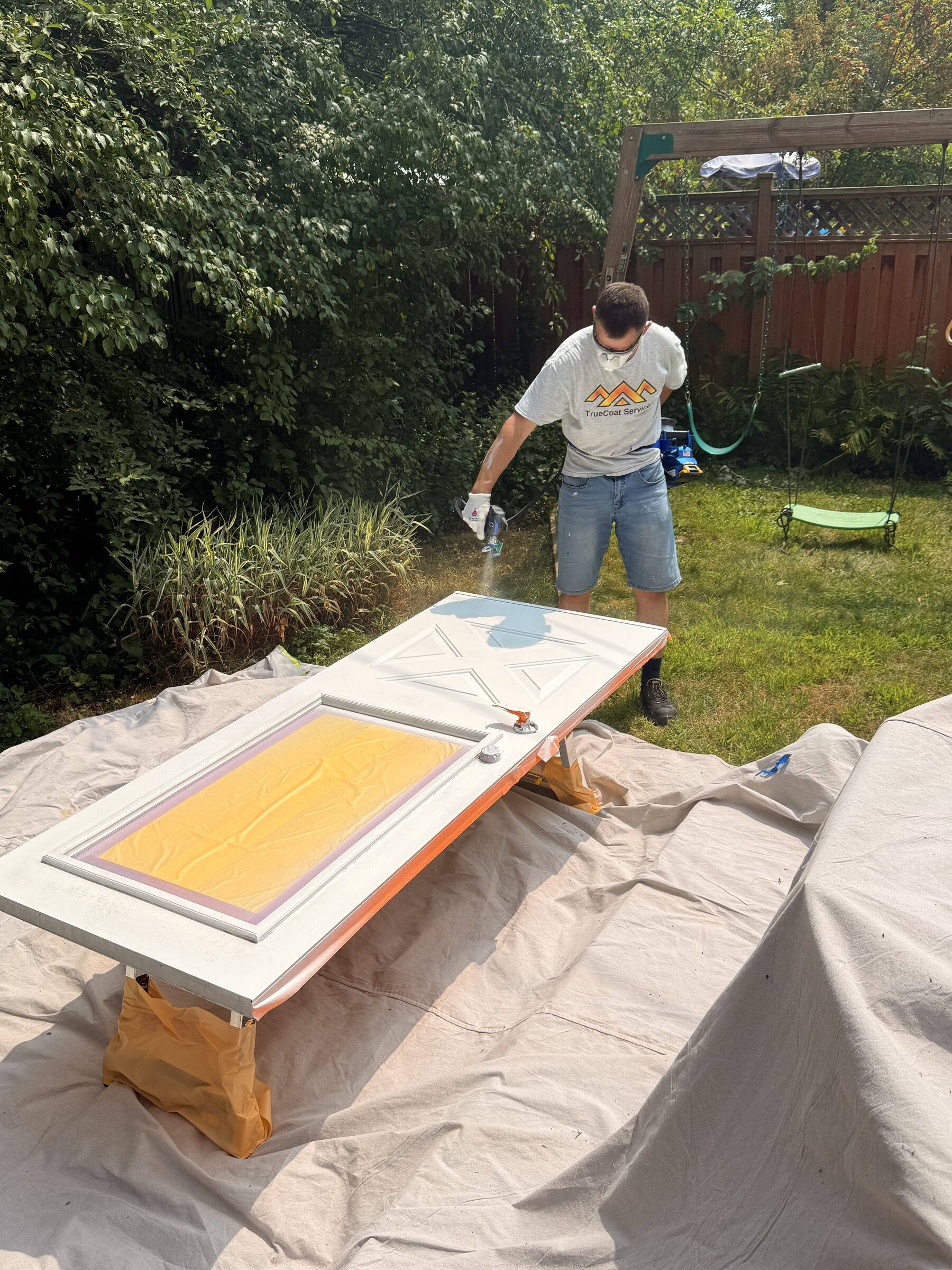 Exterior door being spray-painted in a Rockcliffe Park backyard