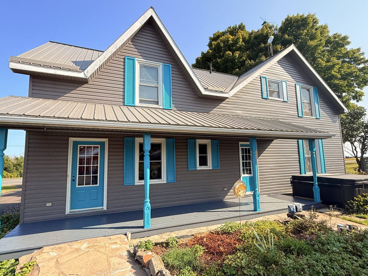 Grey home with white trim, blue shutters and a blue front door after a full exterior repaint in Eastern Ontario.