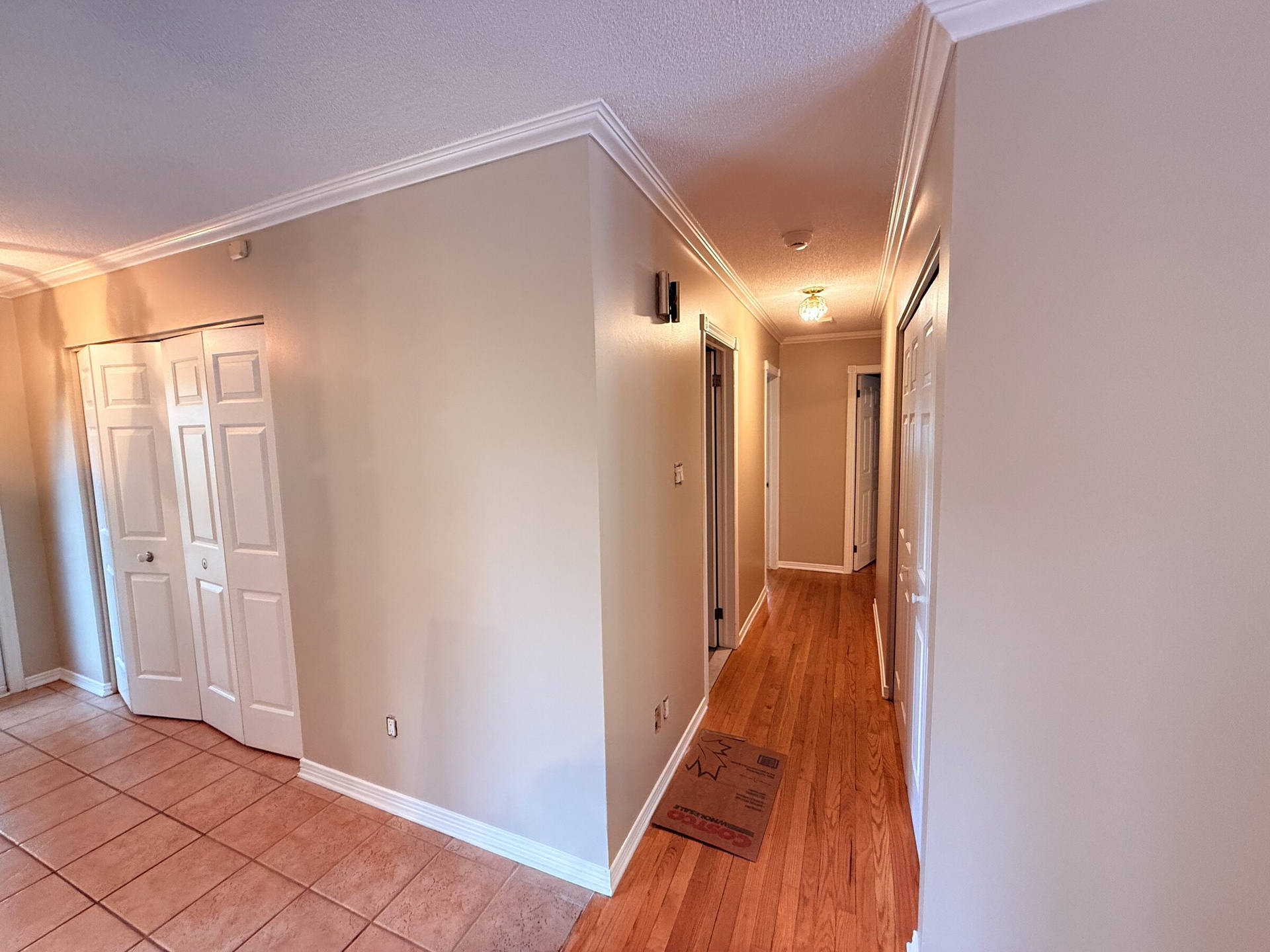 After: Freshly painted hallway in a warm neutral with white trim and crown molding