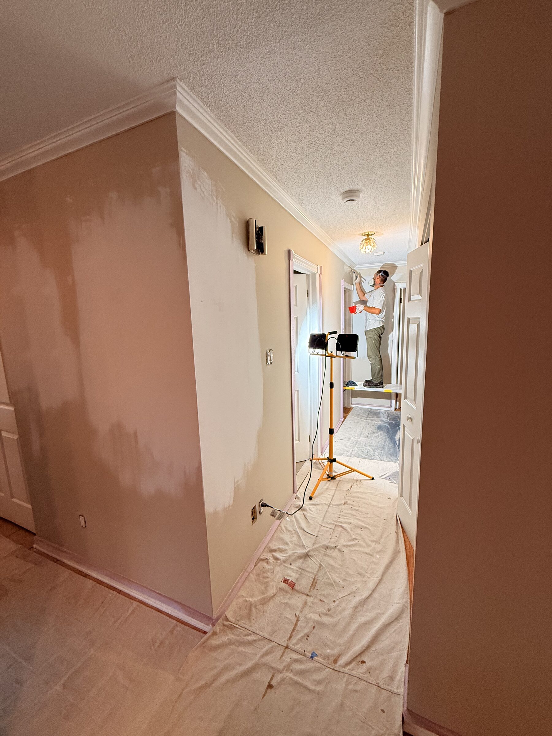 Before: Hallway mid-repaint, the original salmon wall beside a freshly primed section