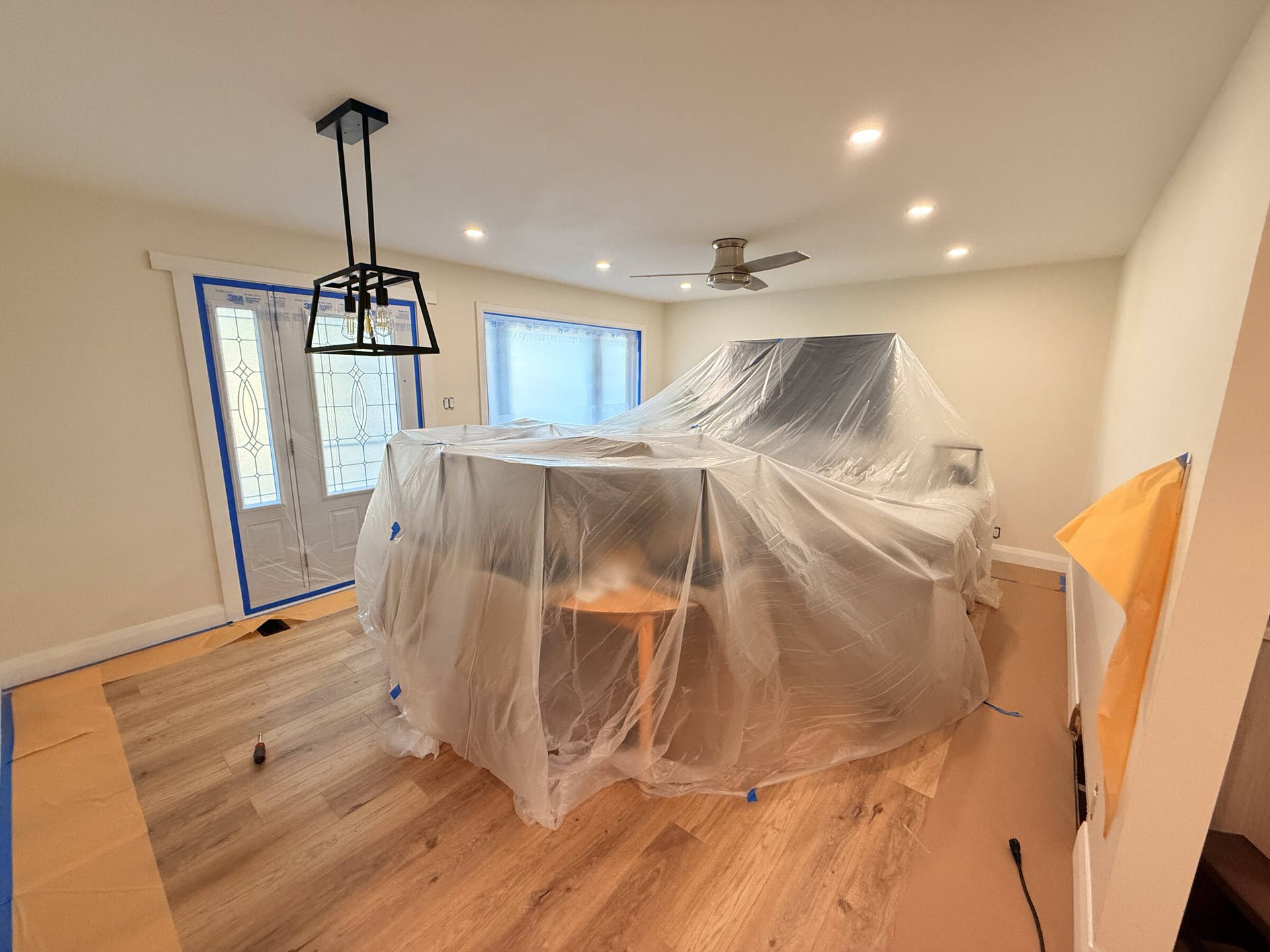 Dining room fully draped in plastic sheeting ahead of interior painting